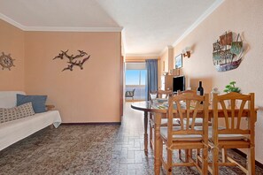 A room with a dining table, chairs, a sofa, and a ship decoration on the wall.