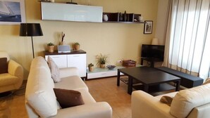 A living room with a sofa, a coffee table, a television, and a cabinet with decorative items.