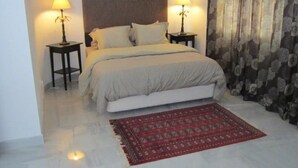 A bedroom with a bed, two bedside tables, a red patterned rug, and a headboard.