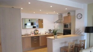 Een moderne keuken met een centraal eiland, houten kastjes en een magnetron.