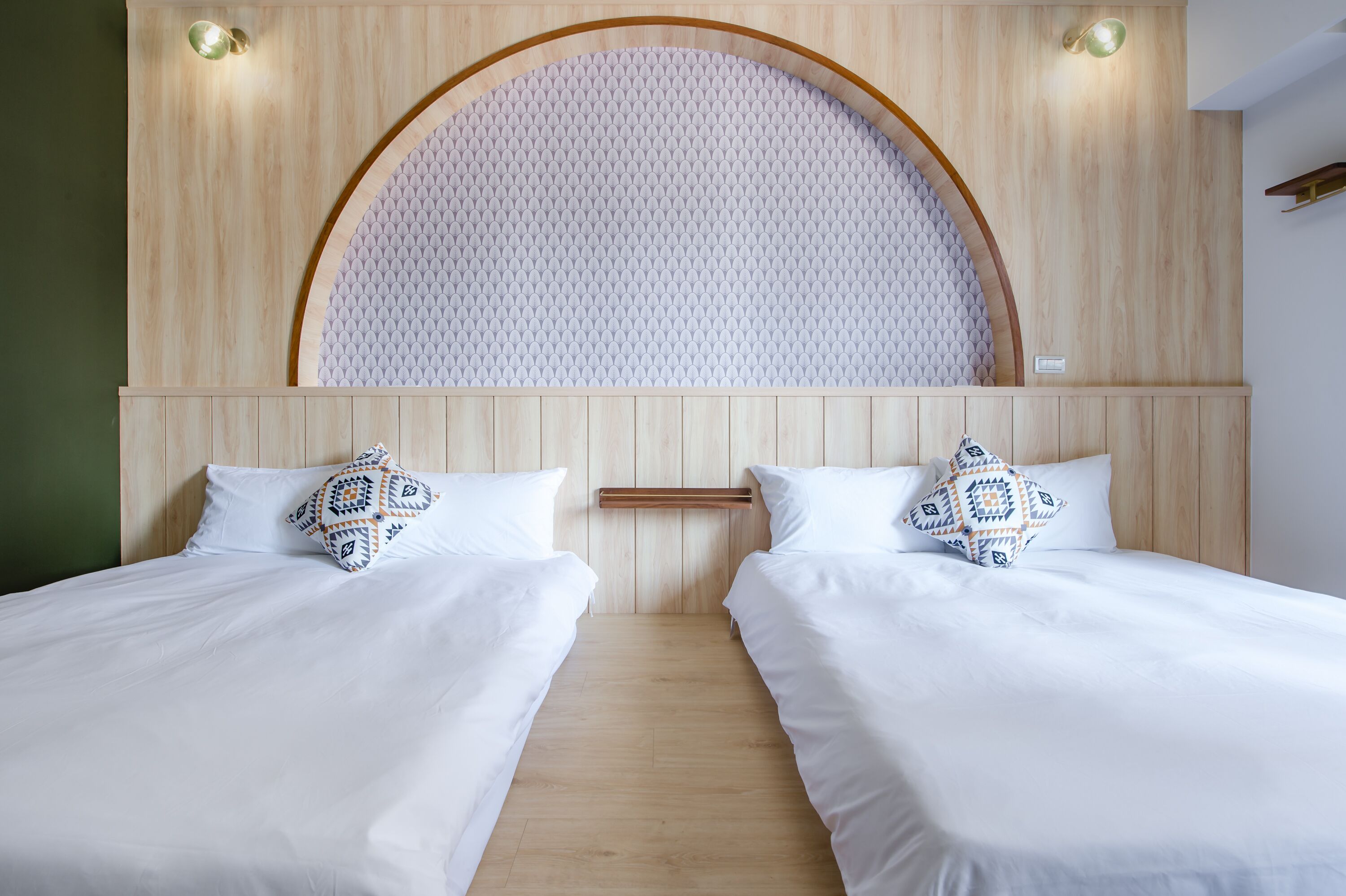 Habitación doble con dos camas, cabecera de madera con diseño circular y pared de color claro.