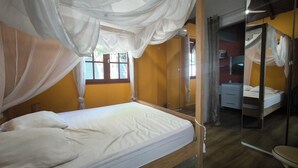 A room with a bed, a mirror, and a window.