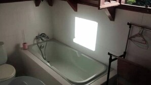 A bathroom with a bathtub, toilet, and a window providing natural light.