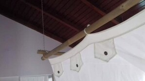 A ceiling with wooden beams and a white fabric structure with holes.