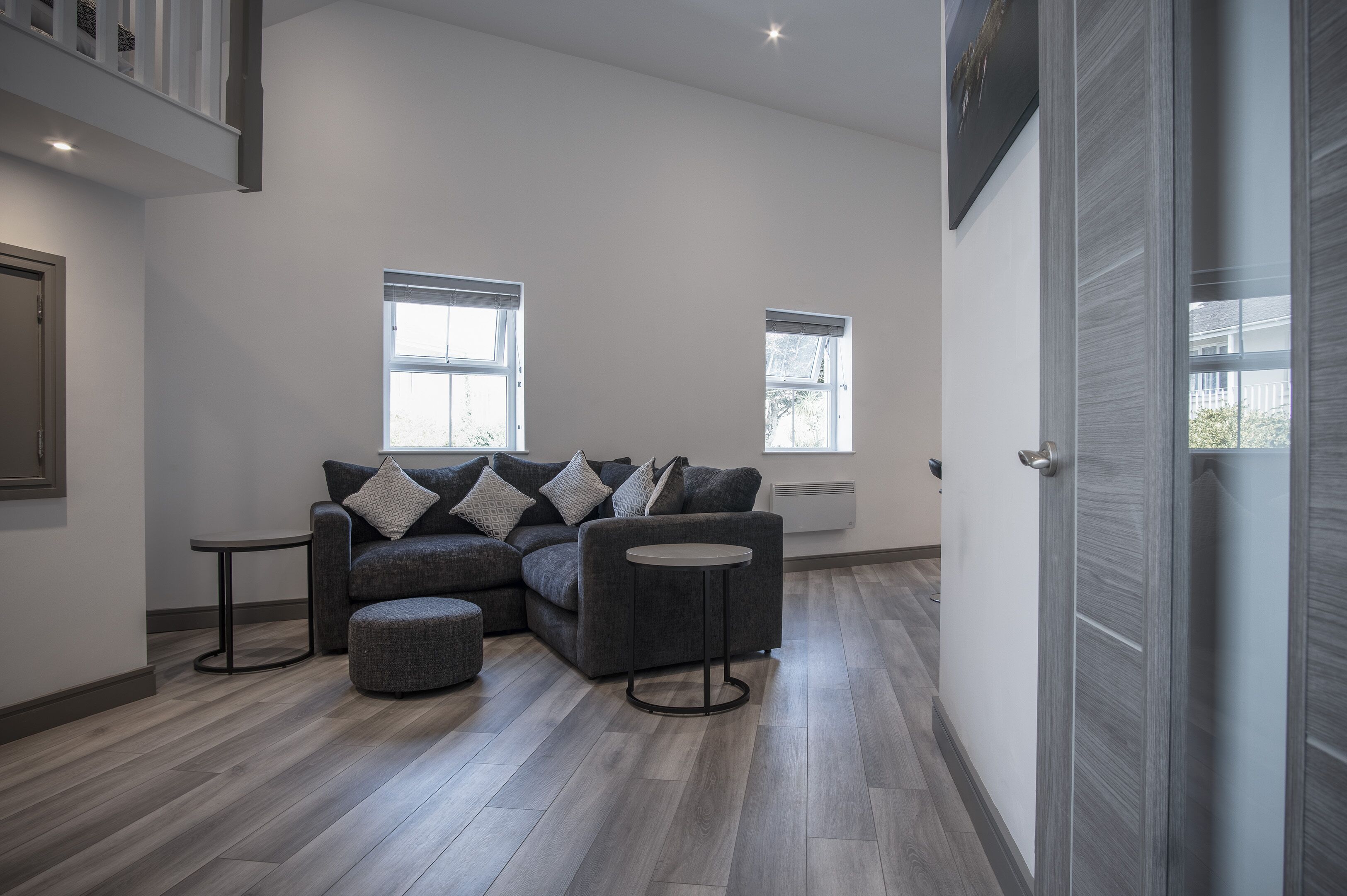 A modern living room with a sectional sofa, ottoman, and two small tables.