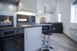 Eine moderne Küche mit Einbauofen, einer Bar mit Hockern und einer Sitzecke mit Sofa.