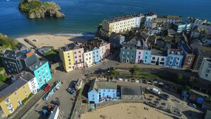 Un pueblo costero con edificios coloridos, una playa y un promontorio rocoso al fondo.