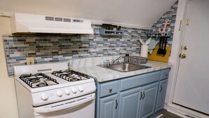 Une cuisine avec un four blanc, des armoires bleues, un pare-feu en carreaux et un plancher en bois.