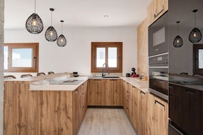 A modern kitchen with wooden cabinets, a central island, a sink, and pendant lighting.