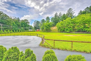Stroll along the paved pathway to a serene grassy field surrounded by a wooden fence and lush hedges.