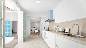 A modern kitchen with white cabinets, a stainless steel sink, and a dining area with a table and chairs. - Apartment 'Albercutx Pollentia 1' with Terrace, Air Conditioning and Wi-Fi (Puerto de Pollensa)