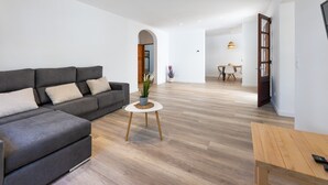 A modern living room with a grey sofa, a small round table with a plant, and a wooden bench. - Apartment 'Albercutx Pollentia 1' with Terrace, Air Conditioning and Wi-Fi (Puerto de Pollensa)
