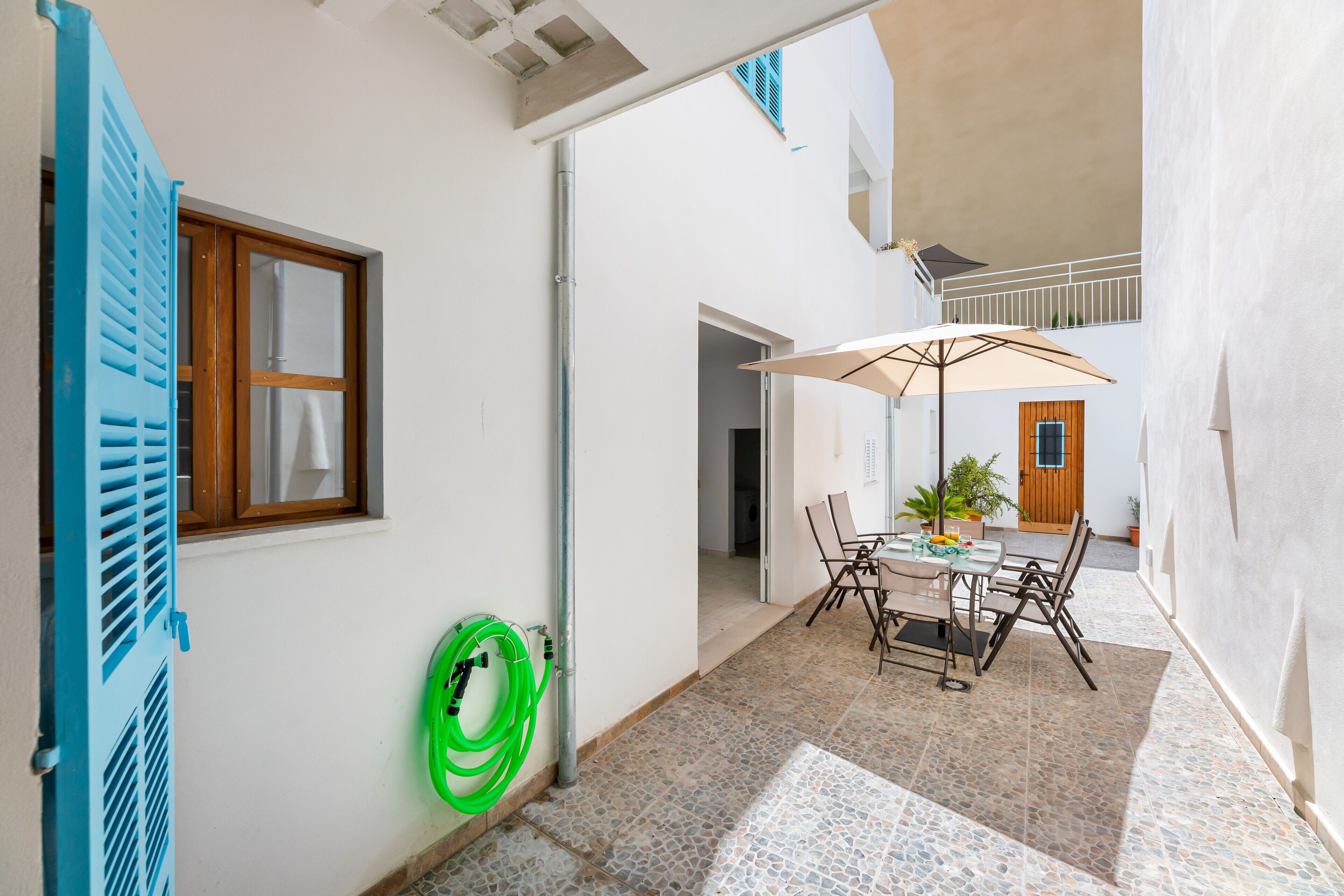 Un cortile con un tavolo, sedie e un grande ombrellone.