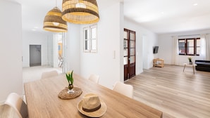 A spacious living area with a wooden dining table, wicker pendant lights, and a black sofa. - Apartment 'Albercutx Pollentia 1' with Terrace, Air Conditioning and Wi-Fi (Puerto de Pollensa)
