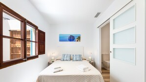 A narrow hotel room with a bed, a painting, and a view of the sea. - Apartment 'Albercutx Pollentia 1' with Terrace, Air Conditioning and Wi-Fi (Puerto de Pollensa)