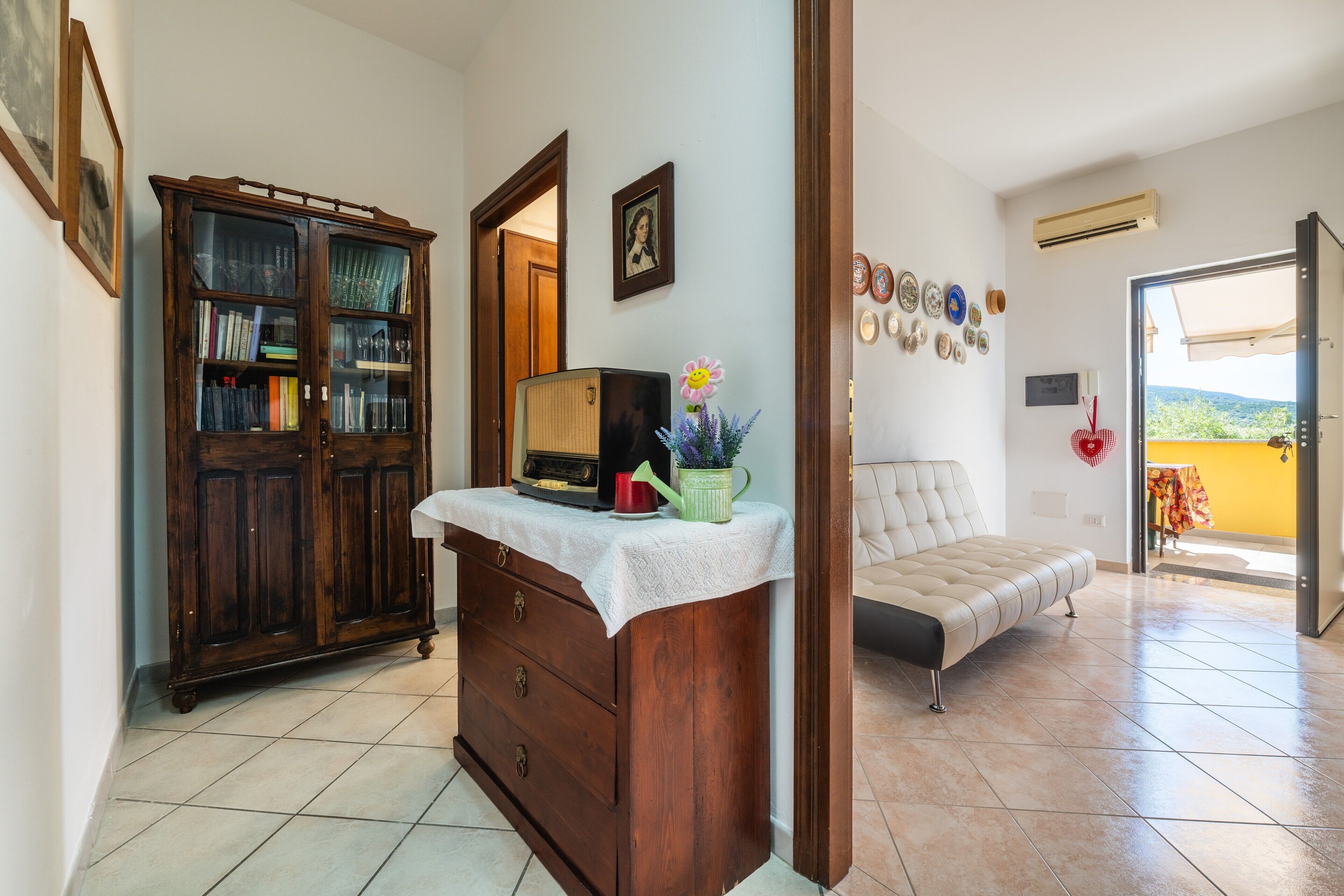 A room with a wooden cabinet, a bed, and a view through an open door.