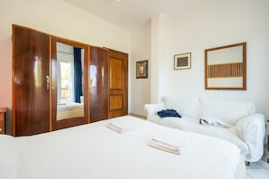 Ein Hotelzimmer mit einem großen Bett, einer weißen Couch, einem Holzschrank und einem Spiegel an der Wand.