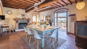 Un comedor con una mesa de madera, sillas, chimenea y vistas al exterior.