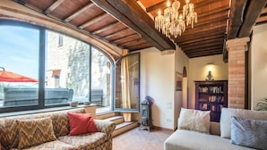Una sala de estar acogedora con un sofá, un sillón adicional, una estantería y un ventanal grande.