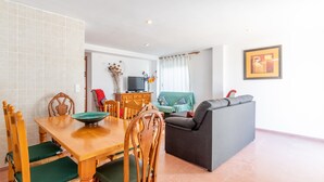 Un salon comprenant une table à manger, des chaises, un canapé, un téléviseur et un tableau encadré accroché au mur.