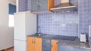 Una cocina con azulejos azules, un refrigerador blanco, gabinetes de madera, un extractor de acero inoxidable y un tostador.