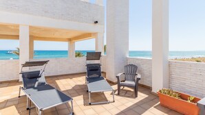 Una terraza con dos sillones, una silla individual y una planta en maceta.