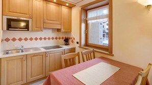 Une cuisine compacte avec des meubles en bois, un four encastré, une fenêtre offrant une belle vue et un coin repas avec une table et des chaises.