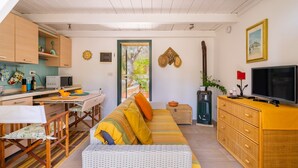 Una sala acogedora con sofá, mesa de comedor, cocina y televisor.