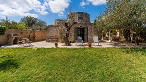 Un edificio de piedra con una torre circular, una puerta y un patio amoblado.
