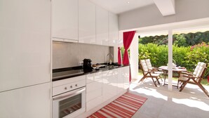 A modern kitchen with white cabinets, a black countertop, and a red-striped rug. - Holiday Apartment 'Large Apartment in Vale do Lobo' with Private Garden & Wi-Fi (Almancil)