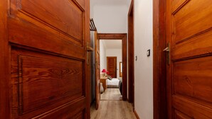 A hallway with wooden doors leading to a bedroom.