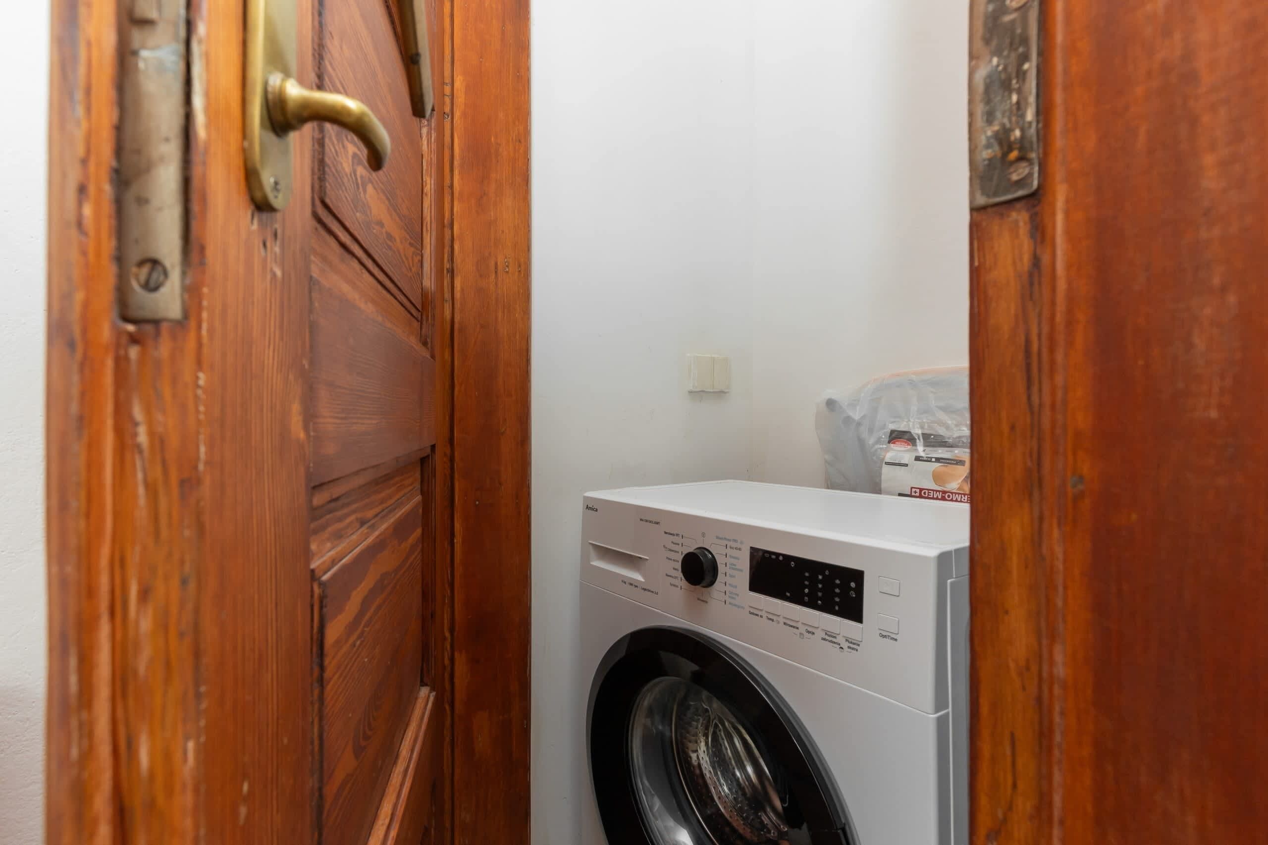 Una lavanderia con una lavatrice bianca e una porta in legno.