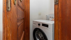 A laundry room with a white washing machine and a wooden door.