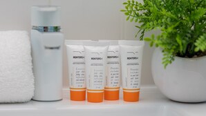 Four bottles of RENTERS® shower gel and a white towel on a bathroom counter.