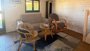 A room with a sofa, two wicker chairs, a small table, a window with a view, and a wooden ceiling. - Apartment with Garden | Parking, 4.9 km to the Beach (Powiat koszaliński)