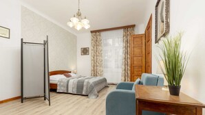 A bedroom with a bed, a desk, a chair, a potted plant, a wardrobe, and a window with curtains.