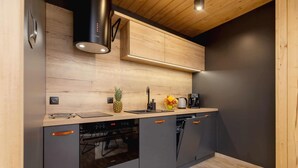 A modern kitchen with wooden cabinets, a built-in oven, and a dishwasher. - Atmospheric Apartment | Mountain View and Workspace (Zakopane)