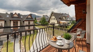 A balcony with a table set for two, a potted plant, and a plate of croissants. - Stylish Apartment | Mountain View, Workspace (Zakopane)