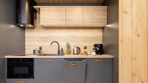A modern kitchen with grey cabinets, a stainless steel range hood, a wooden countertop, and a built-in oven. - Stylish Apartment | Mountain View, Workspace (Zakopane)
