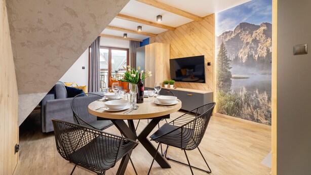A dining area with a round table, black wire chairs, and a view of a mountainous landscape through a large window. - Stylish Apartment | Mountain View, Workspace (Zakopane)