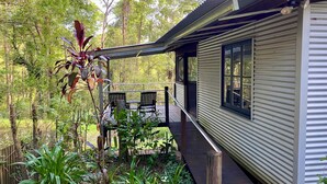 Une cabane dotée d’une terrasse, entourée d’une forêt dense.
