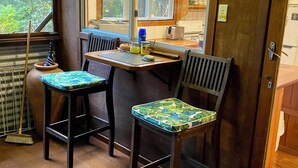 Une cuisine chaleureuse, avec des meubles en bois, une fenêtre donnant sur les arbres et une porte menant à une autre pièce.