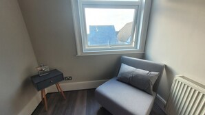 A small, single-bed room with a window, a desk, and a radiator.