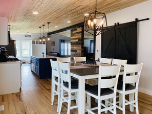 A modern kitchen with a central island, white chairs, and a black barn-style door. - THIS HOME IS TEMPORARILY UNAVAILABLE FOR RENT (Rapid City)