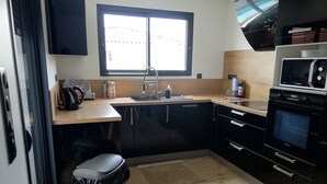 Cozinha compacta com micro-ondas, forno, pia e janela.