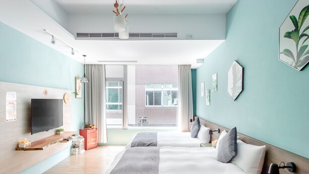 Habitación de hotel moderna con una cama grande, televisión, escritorio y vistas de la ciudad.