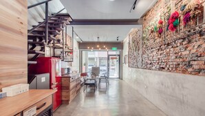 Un interior moderno con una encimera de madera, un refrigerador rojo y una pared de ladrillo con adornos colgantes.