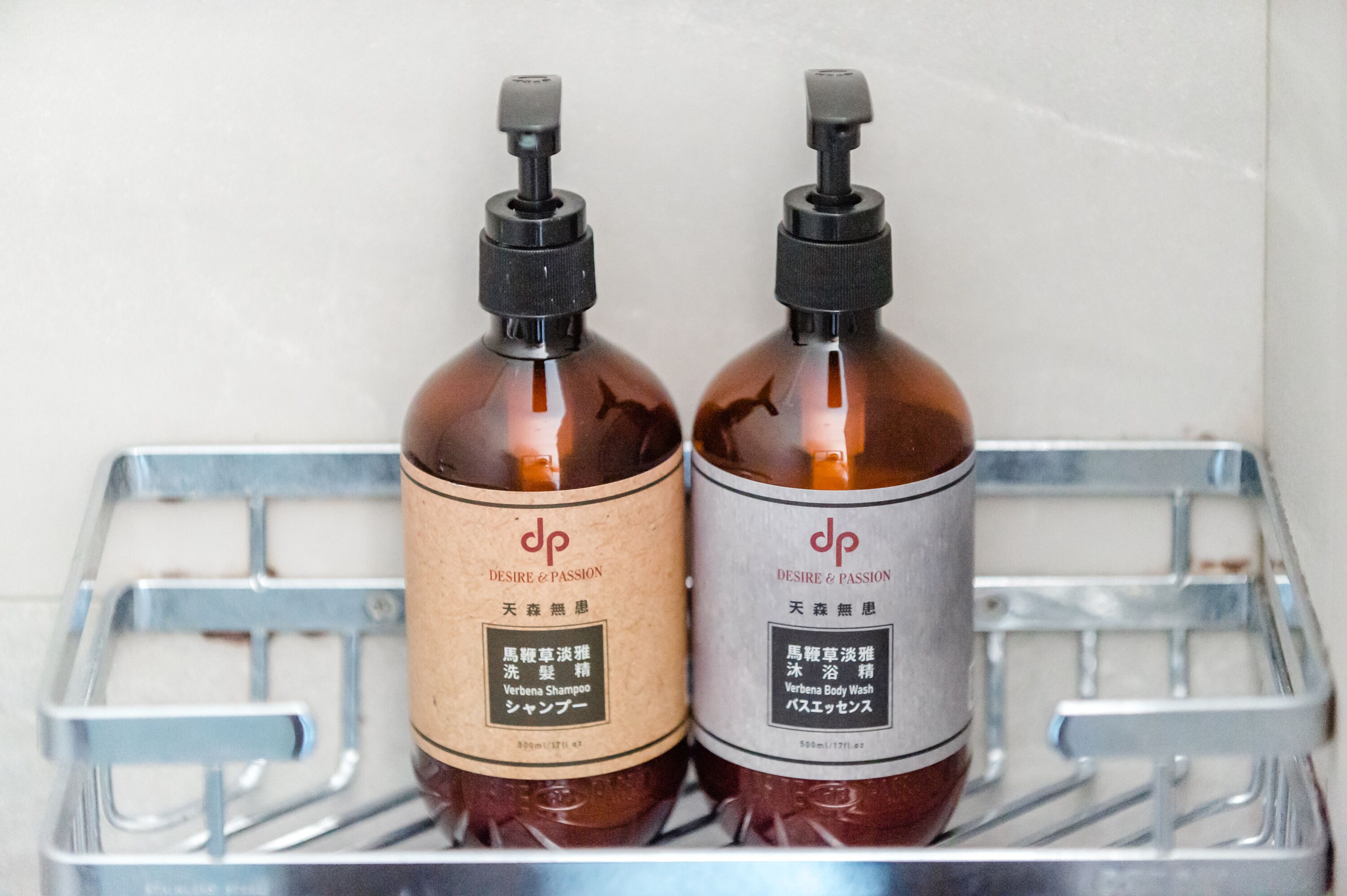 Two bottles of Verbena Shampoo and Body Wash on a metal shelf.