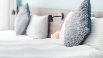 Una cama con ropa de cama blanca y almohadas estampadas con motivos geométricos.