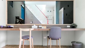 Un espacio de trabajo moderno con un espejo grande, dos sillas, un escritorio y un cubo de basura.